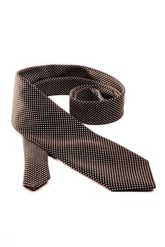 A black tie with white dots rolled out on a white isolated background.