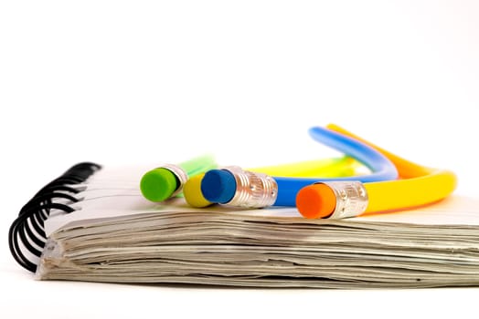 Four colourful pencils that are all strangely bend, lying on a notebook.