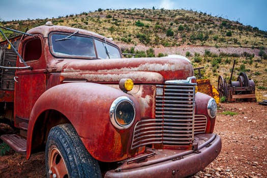 Large rusty old pickup truck rotting out in a field.