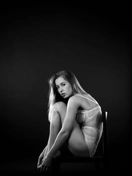 Photo of a sexy young woman posing in her lingerie and sitting on a chair.