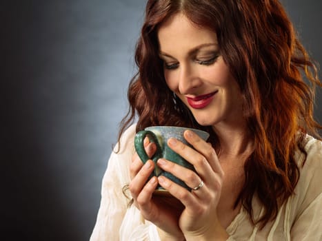 Beautiful happy redhead woman drinking coffee and relaxing.