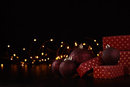 Gift boxes, Christmas decoration with LED lights garland on a black background with copy space. Christmas and New Year shopping. Greeting card