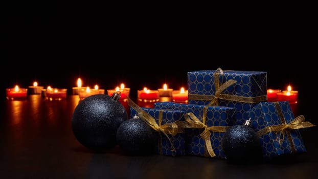 Gift boxes, Christmas decoration with burning candles on a black background with copy space. Christmas and New Year shopping. Greeting card