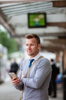 A businessman waiting on a train at the train station to go home from work for the day.