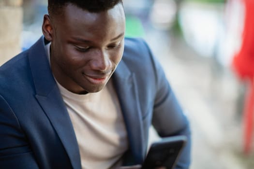 Businessman sitting down  while typing on his mobile phone and smiling.