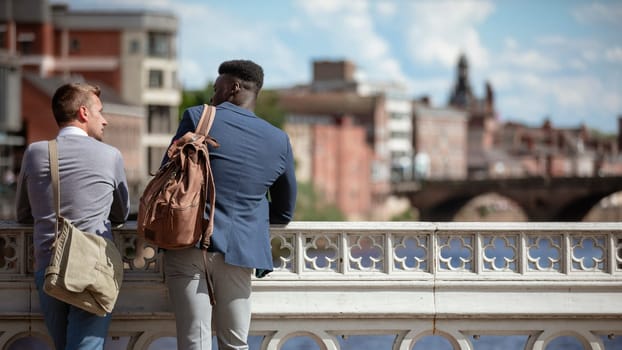 Two businessmen talking while leaning on a bridge in York.They have their backs to the camera.