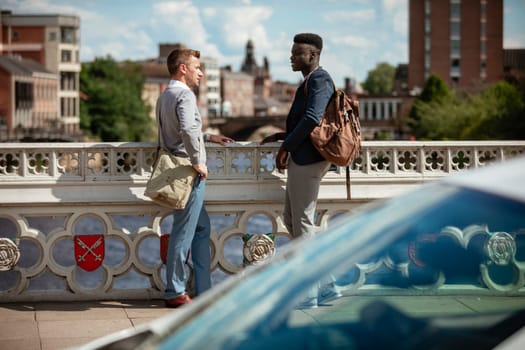 Two businessmen having a chat on a bridge in York. They are facing each other.