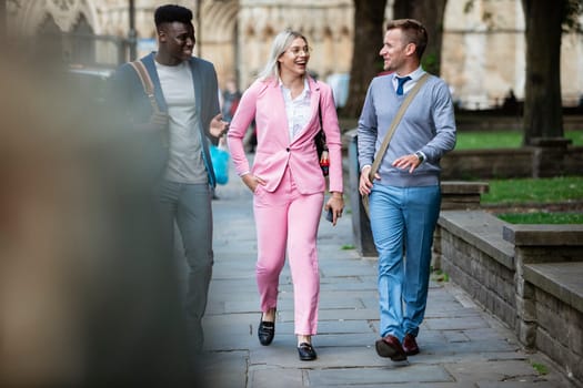 A businesswoman is walking with two businessmen to work through the city.
