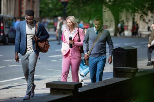 A businesswoman is walking with two businessmen to work through the city.