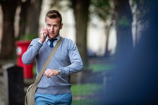 Businessman on his way to work while talking on the phone and about to check the time.