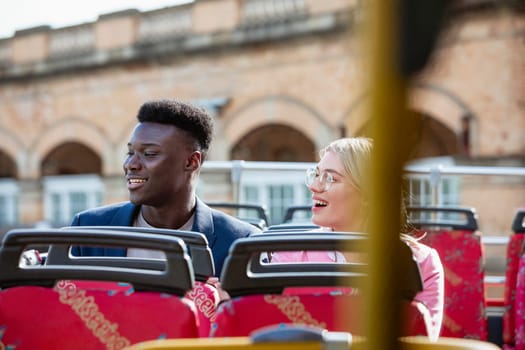 A male and female co-worker taking the bus home from work together, they are smiling while looking at the view.