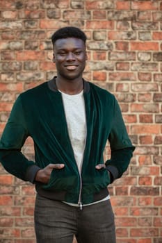 A man standing in front of a brick wall and looking into the camera while smiling.