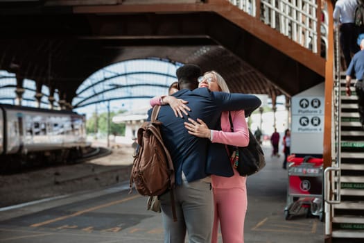 A male and female co-worker parting ways after work. They are hugging each other goodbye.