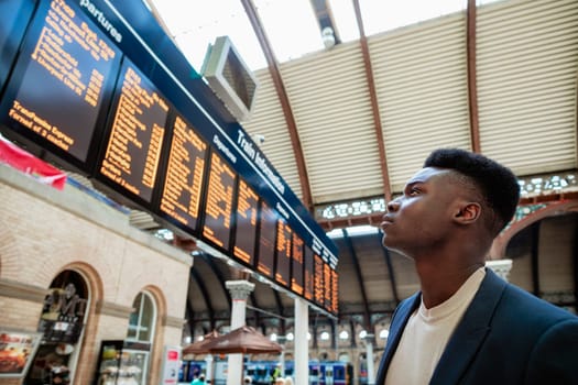 A businessman looking at a departure board in a train station.