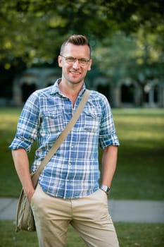 A man standing in a park and looking into the camera while smiling.