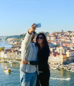 PORTO, PORTUGAL - Couple taking selfie in front of Old Town of Porto, Portugal