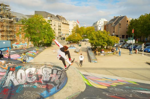 BRUSSELS, BELGIUM - OCTOBER 05, 2019: Teenager jumping in the ramp at a skate park in central Brussels.The Ursulines square is a public open square in skateboarding, BMX, inline skating, etc.