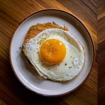 Oeuf au Plat is a simple dish featuring a perfectly cooked fried egg with runny yolk and glossy egg whites.
