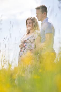 Young happy pregnant couple hugging in nature. Concept of love, relationship, care, marriage, family creation, pregnancy and parenting.