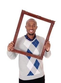 A tall handsome young African American man holding up an old.picture frame, looking trough, isolated for white background.