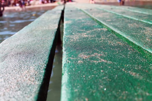 Green wood pier with sand on the sea