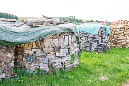 Logs in a metal grid cage covered by a plastic sheet on a lumber yard