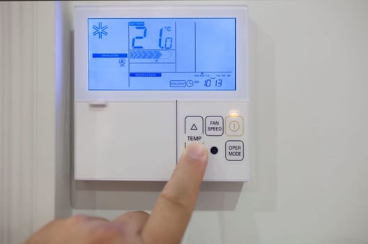 Adjusting room climate control with electronic device at home. Finger pressing for 19 celsius degrees