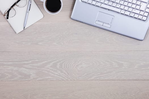 A wood office desk table with coffee, laptop, pen pad and glasses, supplies, top view with copy space