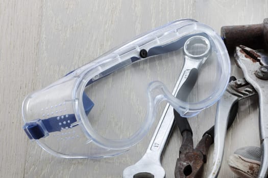 A pair of safety goggles / glasses on a bench with tools