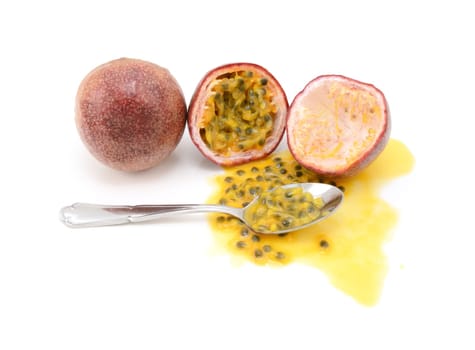 Whole and halved passion fruits ready to eat with a spoon, with spilled juice and sweet seeds, on a white background