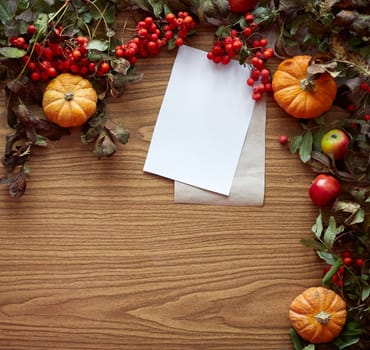 Autumn composition. Pumpkins, dried fall leaves, apples, red berries on wooden table. Flat lay, top view, copy space