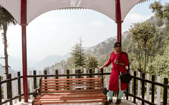 Young woman tourist on vacation standing at Travelers Rest (Entertainment Tent ) one summer morning in a hill station of Himalayas mountains. Front View. Darjeeling, India