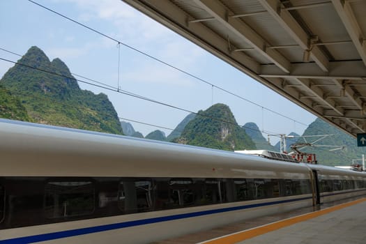 Fragment of a fast train at the station on the background of picturesque mountains, Yangshuo, China