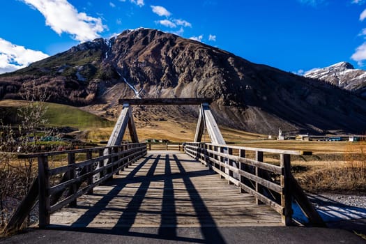 Beautiful mountain valley with stream, trees, footpath and wooden bridge, Livigno is a small town and ski centre for Italian Alps, Italy