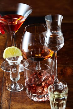 An assortment of alcoholic beverages served in stylish glasses on a wooden bar counter viewed close up high angle in vertical format