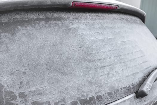 Close - up of frozen rear window of the car, covered with ice  on a winter day.