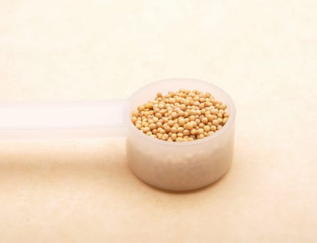 Mustard seeds in measuring spoon on brown background