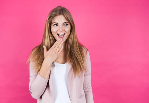 Young blonde girl astonished, isolated on pink background