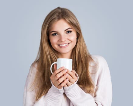 Portrait of a young beautiful woman holding a cup, isolated on grey