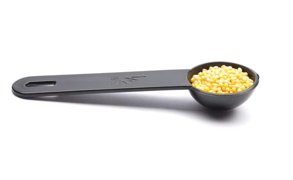 Raw millet in  measuring spoon on white background