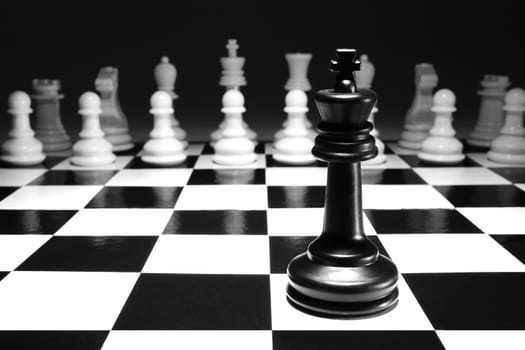 A chess black king single alone against white army concept strategy game one selective focus