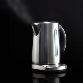 A modern kettle with steam on black reflective surface