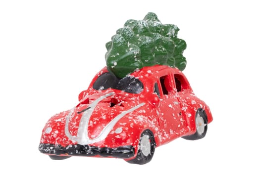 Christmas decorations background. Closeup of a snow-covered red car toy with green fir-tree on the roof isolated on a white background. Saisonal design element for cards or stickers. Macro.