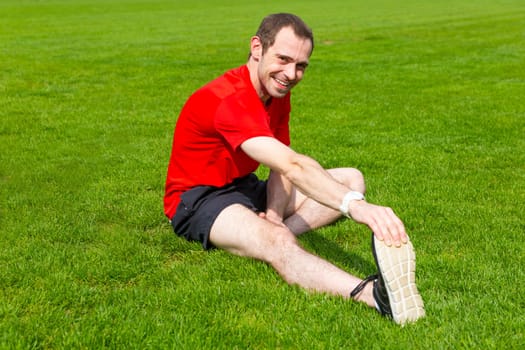 Young handsome sportsman is doing stretching exercises before workout