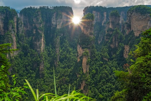 Sun shining through the vertical karst pillar rock formations as seen from the Enchanting terrace viewpoint, Avatar mountains nature park, Zhangjiajie, China