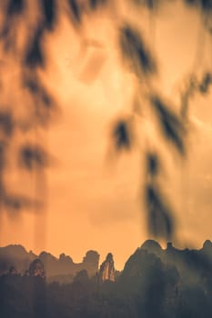 Orange sky above the stunningly beautiful rocky karst mountain formations as seen from the centre of Wulingyuan town, Hunan Province, China