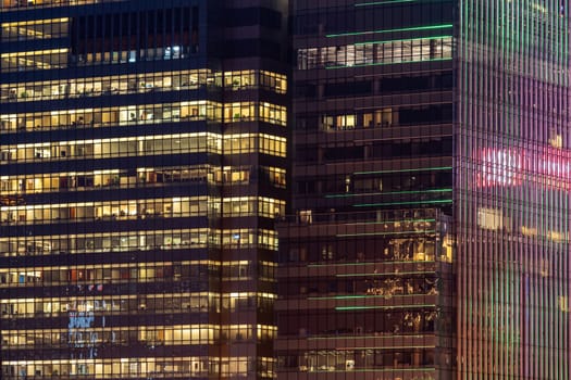Urban abstract - window facade of business center office building with reflections and colours at night. Hong Kong China