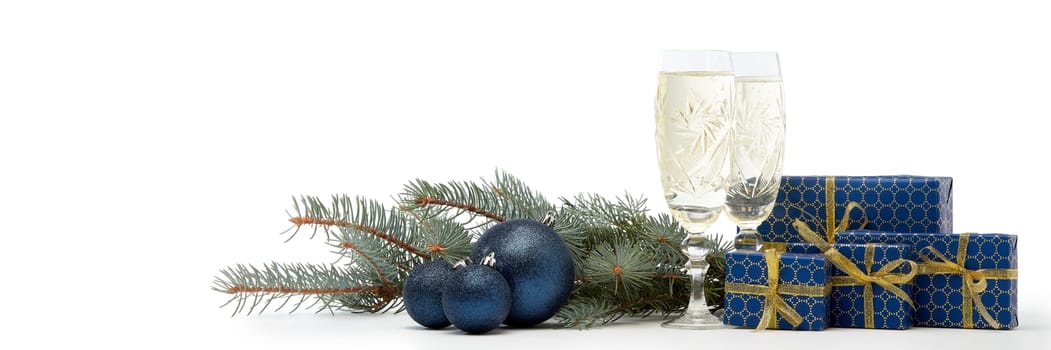 Still life with two champagne flutes, gift boxes and Christmas decoration with fir tree branch isolated on white background with copy space. Christmas and New Year shopping. Greeting card
