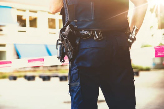 Dutch Policeman on crime scene at school. Red plastic tape police officer, gun belt, handcuffs and gun