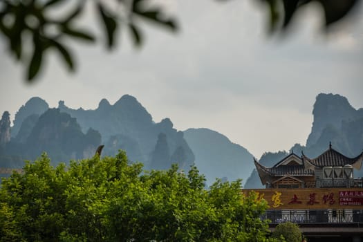 Wulingyuan, China - August 2019 : Rooftops of traditional chinese buildings with the stunningly beautiful rocky karst mountain formations behind as seen from the centre of  town, Hunan Province